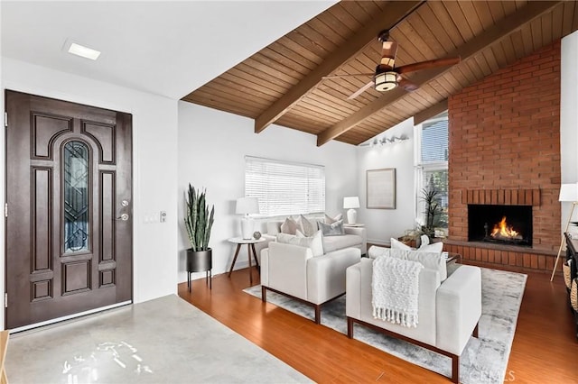 living area featuring ceiling fan, wood ceiling, lofted ceiling with beams, a fireplace, and wood finished floors