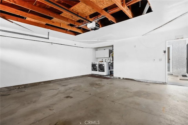 garage with baseboards, a garage door opener, and washer and clothes dryer