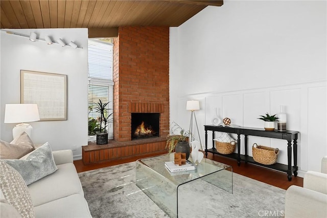 living area featuring lofted ceiling with beams, wood finished floors, wooden ceiling, and a fireplace