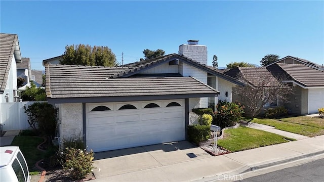 view of front of home featuring a tile roof, concrete driveway, stucco siding, a chimney, and an attached garage