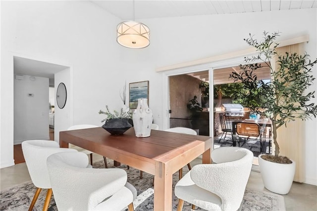 dining area with concrete floors and high vaulted ceiling