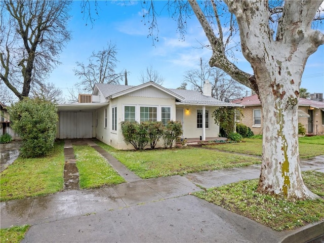 view of front of house featuring a carport, a front yard, a chimney, and driveway