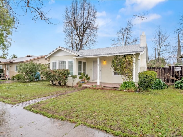 single story home featuring fence, a porch, a front yard, stucco siding, and a chimney