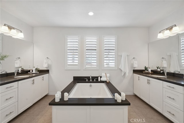 bathroom with a bath, two vanities, and a sink