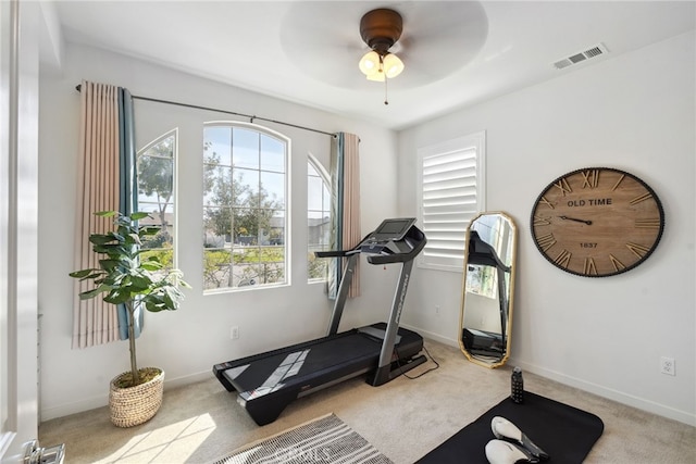 exercise area with visible vents, a ceiling fan, baseboards, and carpet floors