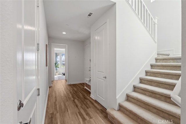 corridor with visible vents, recessed lighting, stairway, and wood finished floors