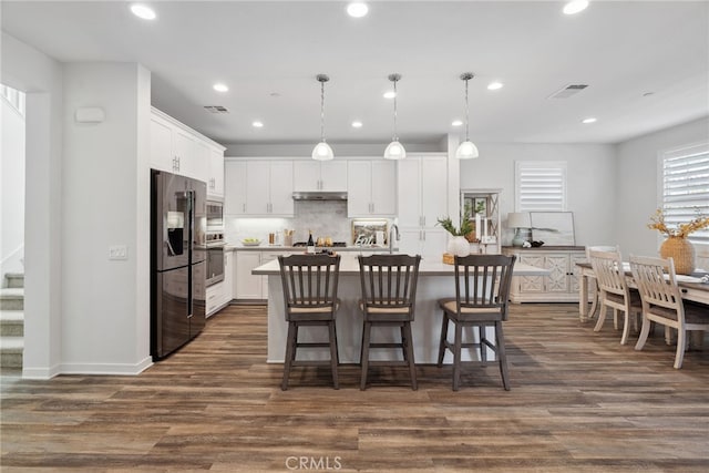 kitchen featuring white cabinetry, under cabinet range hood, visible vents, and appliances with stainless steel finishes