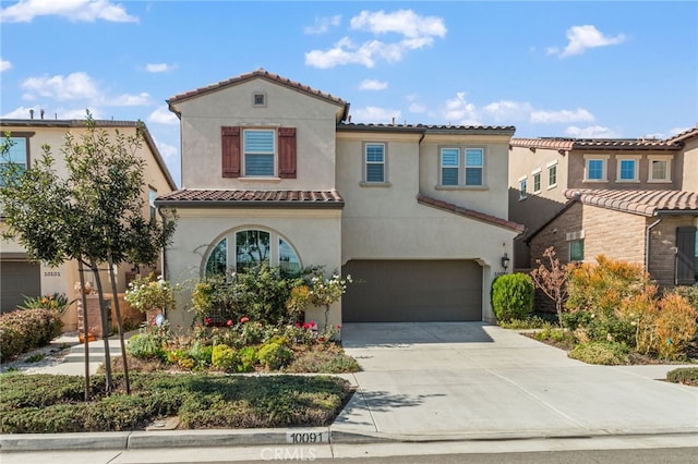 mediterranean / spanish-style house with stucco siding, a garage, concrete driveway, and a tiled roof