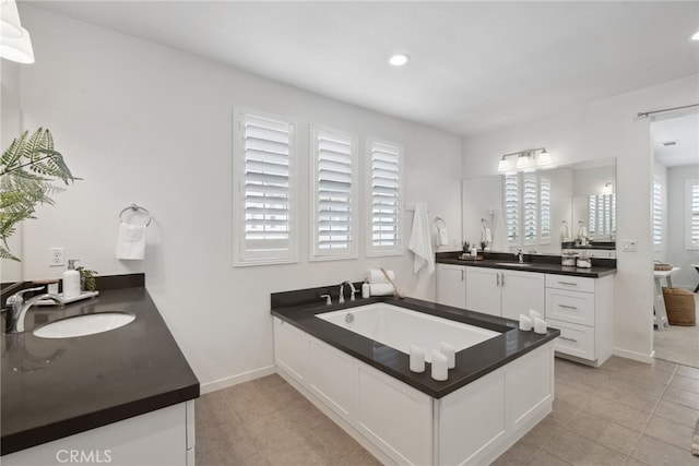 bathroom with a sink, two vanities, a bath, and tile patterned floors