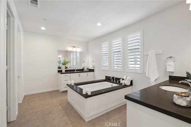 full bathroom with visible vents, a garden tub, two vanities, a sink, and recessed lighting