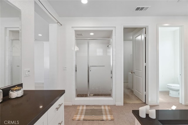 bathroom with vanity, visible vents, tile patterned flooring, a shower stall, and toilet