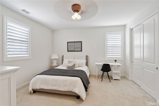 bedroom featuring multiple windows, baseboards, visible vents, and light carpet