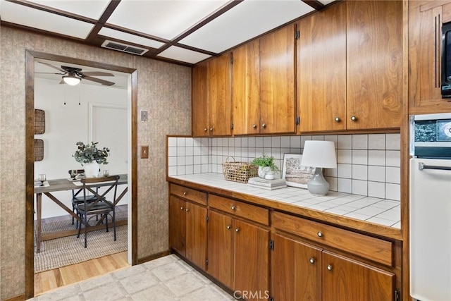 kitchen featuring visible vents, brown cabinets, oven, and tile counters