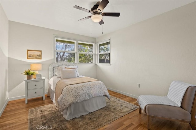 bedroom featuring ceiling fan, baseboards, and wood finished floors