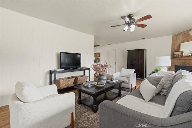 living area with a ceiling fan and wood finished floors