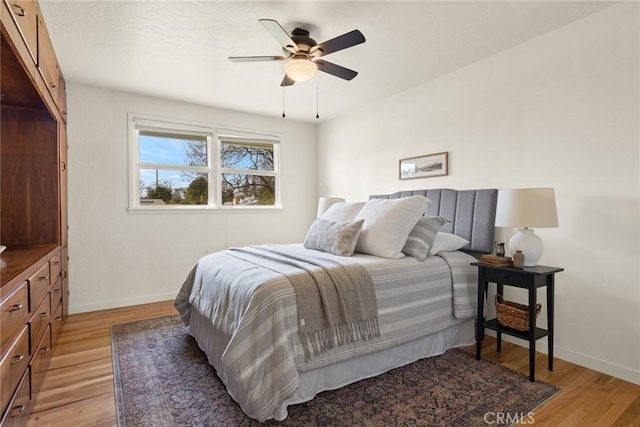 bedroom with a ceiling fan, baseboards, and light wood finished floors