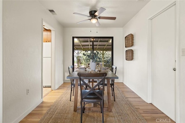 dining space featuring visible vents, baseboards, light wood-type flooring, and a ceiling fan