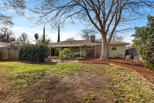 rear view of house with a patio, fence, a yard, central AC, and a chimney