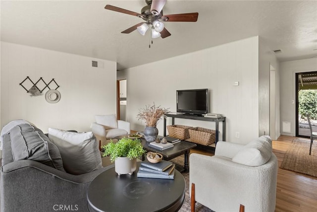 living room with visible vents, a textured ceiling, a ceiling fan, and wood finished floors