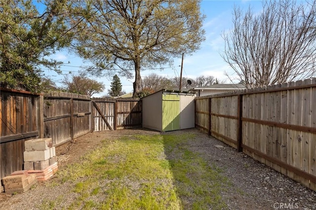 view of yard featuring a storage shed, a fenced backyard, and an outbuilding