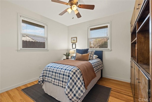 bedroom with light wood-type flooring, multiple windows, and baseboards