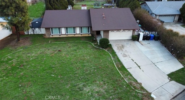 exterior space with fence, driveway, an attached garage, a front lawn, and brick siding