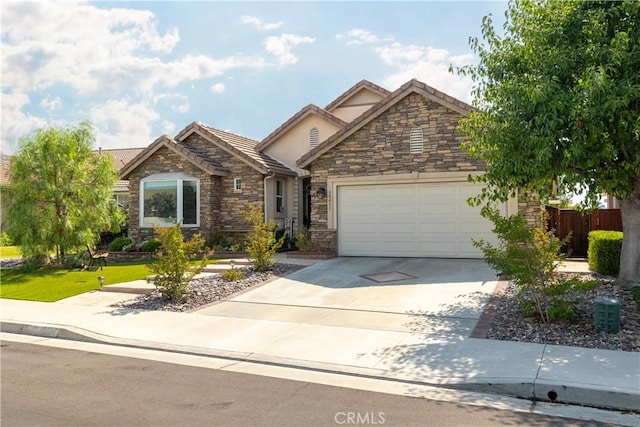 view of front of home with fence, stucco siding, a garage, stone siding, and driveway