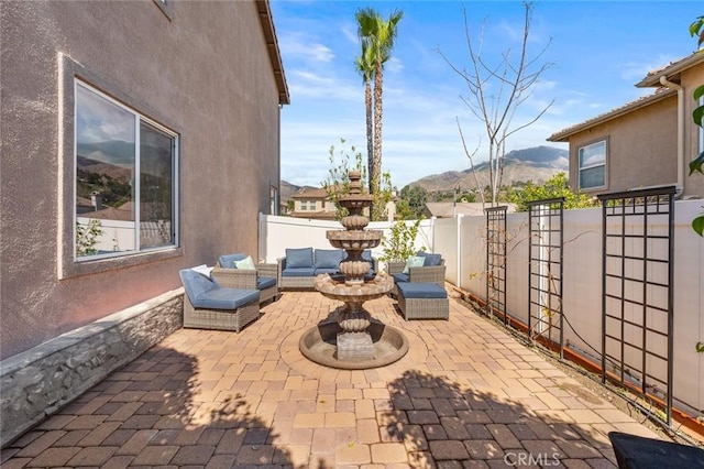 view of patio / terrace featuring an outdoor living space, a mountain view, and a fenced backyard