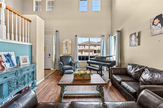 living room featuring baseboards, a towering ceiling, and wood finished floors