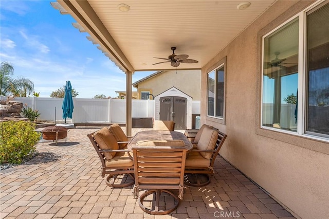 view of patio featuring an outbuilding, a ceiling fan, a shed, outdoor dining area, and a fenced backyard