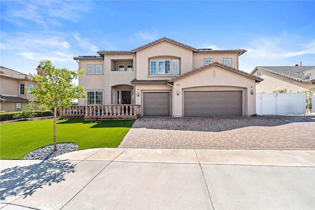 mediterranean / spanish house featuring fence, a tiled roof, a front yard, stucco siding, and decorative driveway