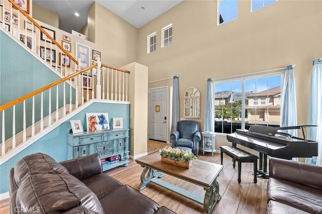 living room with stairway, baseboards, wood finished floors, and a towering ceiling