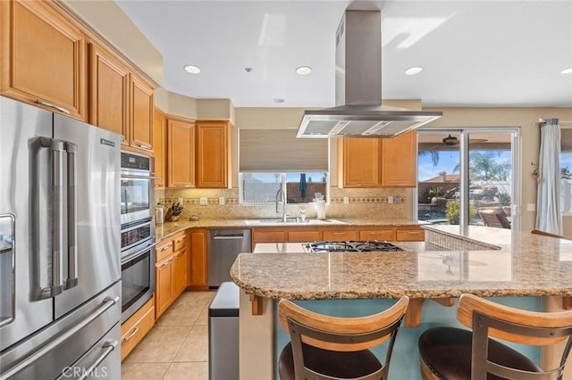 kitchen with tasteful backsplash, light tile patterned floors, island exhaust hood, stainless steel appliances, and a sink