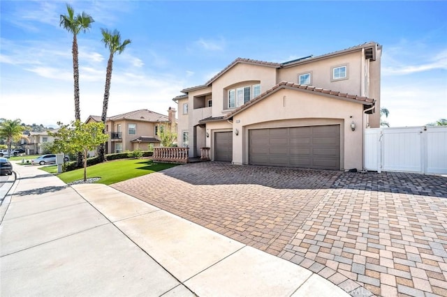 view of front facade with fence, stucco siding, decorative driveway, an attached garage, and a gate