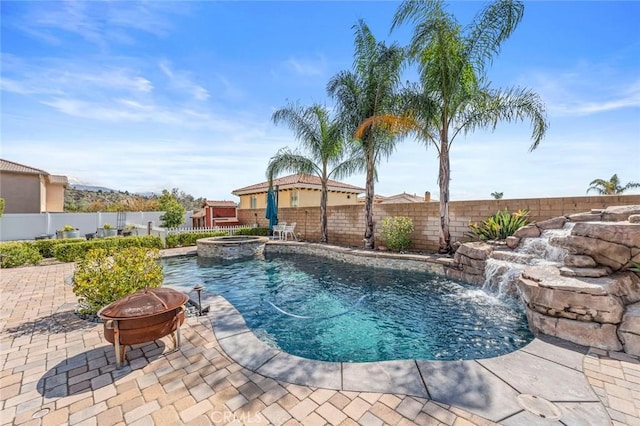 view of swimming pool featuring a patio area, a pool with connected hot tub, a fire pit, and a fenced backyard