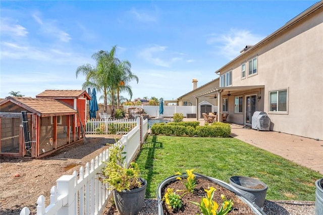 view of yard featuring exterior structure, a patio, a fenced backyard, an outdoor structure, and ceiling fan