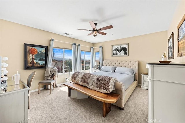 bedroom featuring visible vents, light colored carpet, baseboards, and ceiling fan