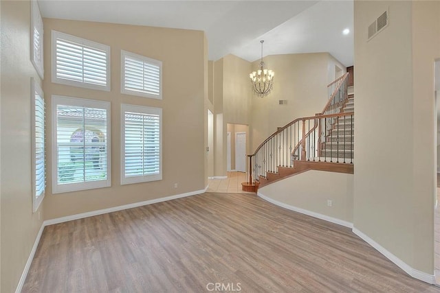 foyer with stairway, a high ceiling, wood finished floors, and baseboards