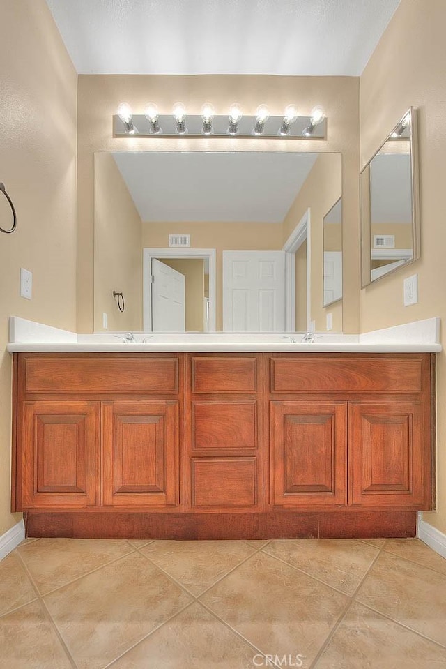 full bath featuring tile patterned floors, double vanity, visible vents, and baseboards