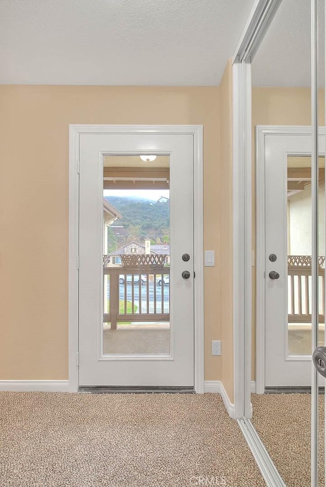 entryway with baseboards and carpet flooring