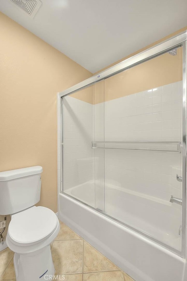 bathroom with tile patterned floors, visible vents, bath / shower combo with glass door, and toilet