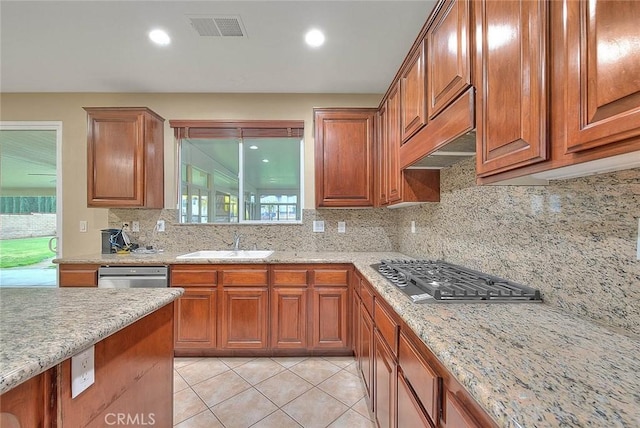 kitchen with visible vents, a sink, stainless steel appliances, decorative backsplash, and light stone countertops