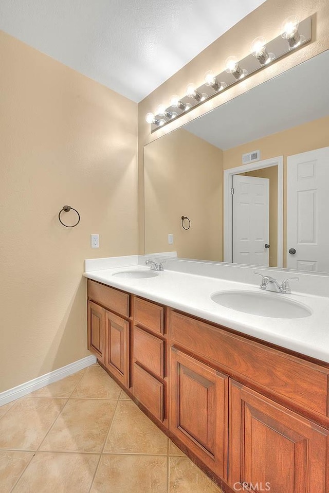 bathroom with double vanity, baseboards, tile patterned floors, and a sink