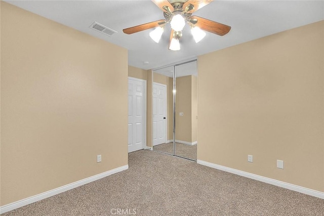 unfurnished bedroom with baseboards, visible vents, carpet floors, and ceiling fan