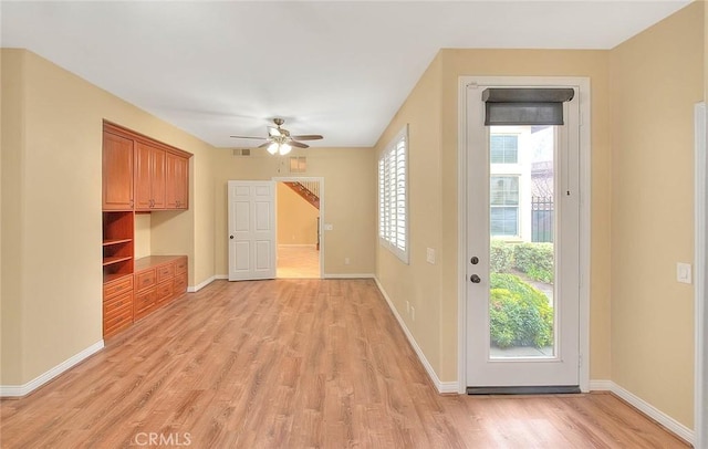 interior space featuring a wealth of natural light, baseboards, light wood-style floors, and ceiling fan