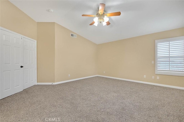 spare room featuring carpet, visible vents, baseboards, ceiling fan, and vaulted ceiling