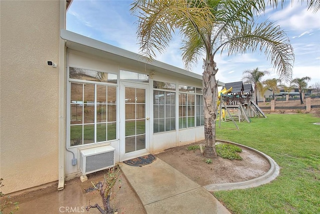 exterior space featuring a lawn, fence, a wall unit AC, and stucco siding