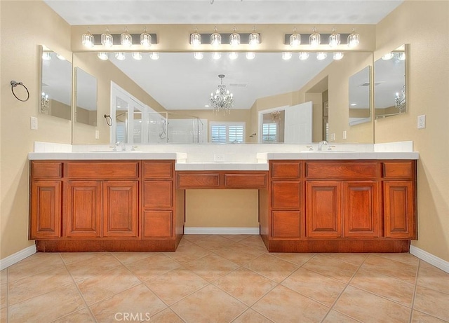 bathroom with an inviting chandelier, double vanity, a stall shower, and a sink