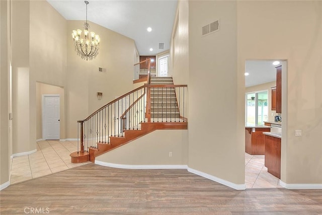 staircase with visible vents, a high ceiling, and wood finished floors