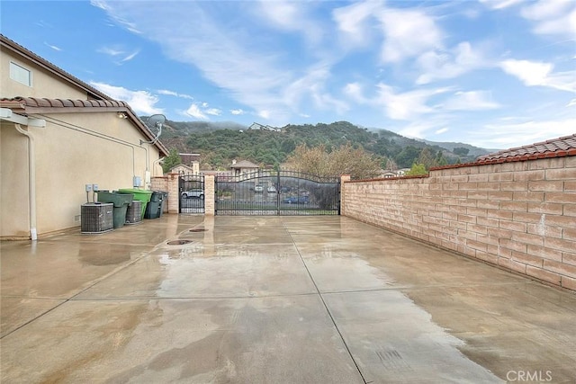 view of patio / terrace featuring a mountain view, fence, central AC unit, and a gate